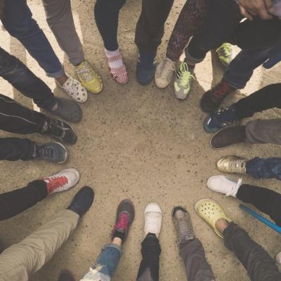 Top view of feet of people standing in a circle. Runners standing in a huddle with their feet together.
